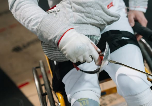Close-up of a wheelchair fencer gripping a sabre, showcasing focus and determination in sport