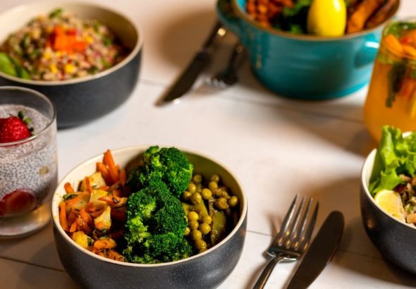 Delicious colorful bowls of salad and fresh beverages on a white table, perfect for healthy dining.